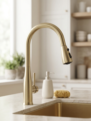 Gold kitchen faucet on a countertop with a neutral background